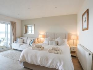 a white bedroom with a large bed and a couch at White Sails in Y Felinheli