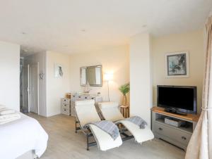 a bedroom with a bed and a tv and two chairs at White Sails in Y Felinheli