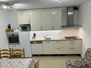 cocina con armarios blancos, fregadero y mesa en Apartments Mrakič, en Bovec