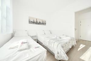 two beds in a room with white walls at ApartamentyPrzyMorzu Strzelecka 33 z parkingiem in Kołobrzeg