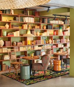 eine Bibliothek mit einem Tisch, Stühlen und Bücherregalen in der Unterkunft Hôtel Oré, Saint-Malo in Saint-Malo