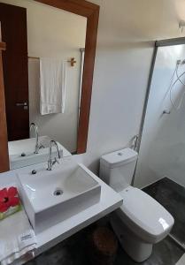 a bathroom with a sink and a toilet and a mirror at D'Ajuda Flat Taipu Bangalôs in Taipu