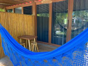 a hammock on a screened in porch with a table at D'Ajuda Flat Taipu Bangalôs in Taipu