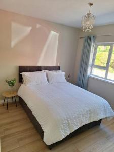 1 dormitorio con 1 cama grande y lámpara de araña en 'Grange Hideaway' Town Centre (Sleeps 6), en Omagh