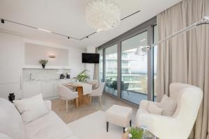 a living room with white furniture and a kitchen at Wave Międzyzdroje Luxury Apartment MORENORENT in Międzyzdroje
