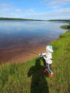 a young child holding a fishing rod on a lake at Riverside Villa in Rovaniemi