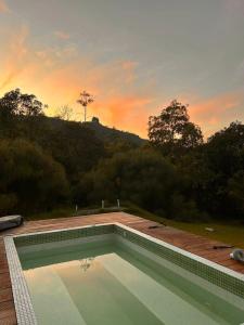 a swimming pool with a sunset in the background at Renacer Santa Elena in Medellín