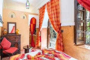 een slaapkamer met een bed, een stoel en een raam bij Riad Osawa in Marrakesh