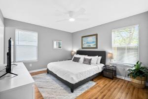 a bedroom with a bed and two windows at Peaceful Pearl Retreat- 5 Minutes to Downtown, 10 Minutes to Beach in Saint Augustine
