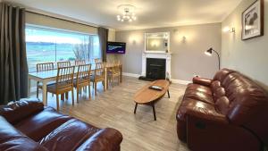 uma sala de estar com um sofá e uma mesa e uma sala de jantar em Blacksmith holiday cottage near Portree in central Skye em Portree