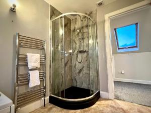 y baño con ducha y puerta de cristal. en Blacksmith holiday cottage near Portree in central Skye, en Portree