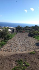 a cobblestone road with the ocean in the background at Dammusielenas in Pantelleria