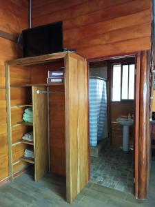 a bathroom with a tv on a wooden wall at Cabaña la granja in Liberia