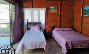 two beds in a room with wooden walls at Cabaña la granja in Liberia