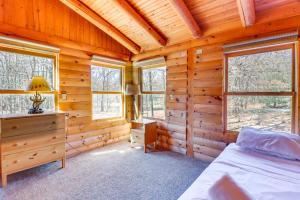 a bedroom in a log cabin with a bed and windows at Private Hot Tub and Fire Pit Log Cabin in Blakeslee in Blakeslee