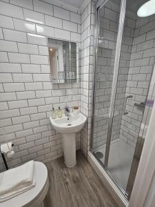 a white bathroom with a sink and a shower at The Beacons Guest House in Brecon +24 photos