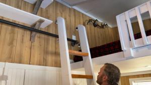 a man standing in front of a staircase in a room at The Notch Hostel in North Woodstock