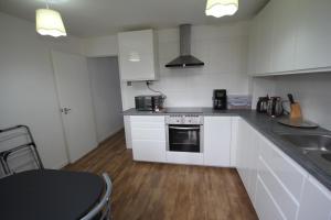 a kitchen with white cabinets and a stove and a sink at Lee's Lodge - Modern 2 Bedrooms in Hillingdon