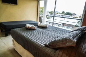 1 dormitorio con 1 cama con 2 toallas en Atardeceres Apartments en Cañuelas