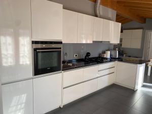 a kitchen with white cabinets and a black microwave at River House in Porlezza