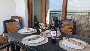 a table with two plates and a bottle of wine at Santa Marina Holiday Village - Purple Harmony Sea view in Sozopol