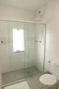 a bathroom with a glass shower with a toilet at Amplo apto próximo a Praia in Garopaba