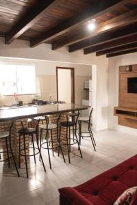 a kitchen with a bar with stools in a room at Amplo apto próximo a Praia in Garopaba