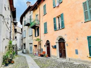 an alley with an orange building with green shutters at FANTASTI-Casa al Lago in Colonno