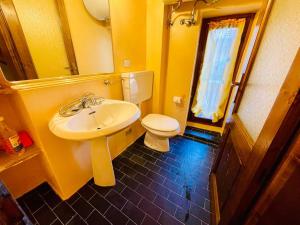 a yellow bathroom with a sink and a toilet at FANTASTI-Casa al Lago in Colonno +35 photos
