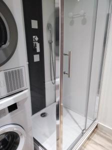 ducha con puerta de cristal junto a una lavadora en Studio des Marches de Bretagne, en Fougères