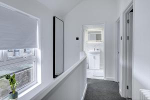 baño blanco con lavabo y ventana en 4 Bedrooms Homely House with Garden- Sleeps 9 Comfortably with 6 Comfortable Beds, Free Street Parking, Business Travellers, Contractors, & Holiday-Goers, Coventry, Near All Major Transport Links in Coventry and Motorway, en Coventry