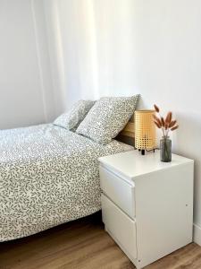 ein weißes Schlafzimmer mit einem Bett und einem Nachttisch in der Unterkunft Acogedor apartamento enfrente de la catedral in Tarragona