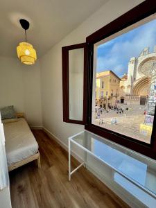 a bedroom with a large window with a view of a city at Acogedor apartamento enfrente de la catedral in Tarragona