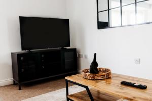 a living room with a tv and a table at Golden Flatts Apartment in Hartlepool
