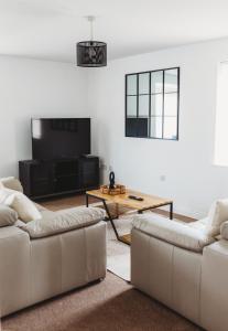 a living room with two couches and a tv at Golden Flatts Apartment in Hartlepool