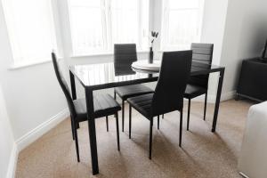 a dining room table with black chairs and a glass table at Golden Flatts Apartment in Hartlepool