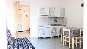 une cuisine avec des placards blancs et une table avec des chaises dans l'établissement Villetta Giuseppe CASA VACANZE NEL SALENTO, à San Foca