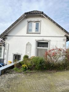 a white house with windows and a driveway at Ferienhaus Weserblick am Sandstrand mit Dart, Billard und Tischkicker in Berne