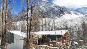 a house with a snow covered mountain in the background at Hostal Crisol in Refugio Lo Valdés