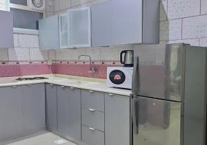 a kitchen with white cabinets and a refrigerator at نور المنازل للوحدات السكنية in Qarār