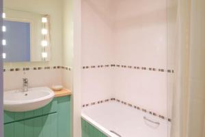 a white bathroom with a sink and a mirror at Flat 2 Mawgan Porth Golf Club in Mawgan Porth