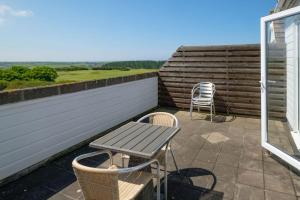 a patio with a table and chairs on a balcony at Flat 2 Mawgan Porth Golf Club in Mawgan Porth