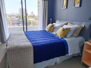 Dormitorio azul con cama con almohadas amarillas en Vivir en Santiago en Santiago