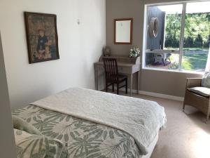 a bedroom with a bed and a desk and a window at Wood Pigeon Cottage Pet Friendly Free Breakfast Hauraki Rail Trail 2kms in Waikino