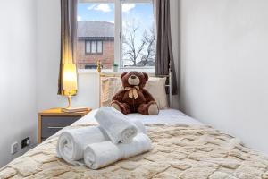a teddy bear sitting on top of a bed with towels at Quirky Canary 2Bed, Free Parking, Smart TV & Games in London