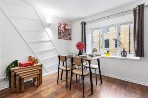 a dining room with a table and chairs next to a window at Quirky Canary 2Bed, Free Parking, Smart TV & Games in London