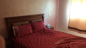 een slaapkamer met een bed met rode lakens en een raam bij شقة لقضاء عطلة مميزة بمدينة الفنيدق in Riffiene