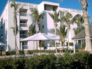 a white building with palm trees and an umbrella at Le Vele Resort in Grace Bay