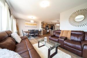 uma sala de estar com sofás de couro castanho e uma mesa em 3BDRM Home, 5min to WEM/4min to River Cree Casino em Edmonton