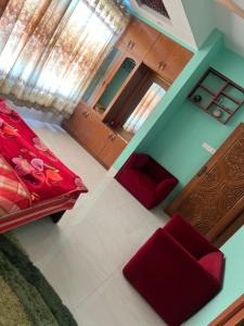a room with a bed and two red chairs at Nice Luxury Suites in Rājshāhi